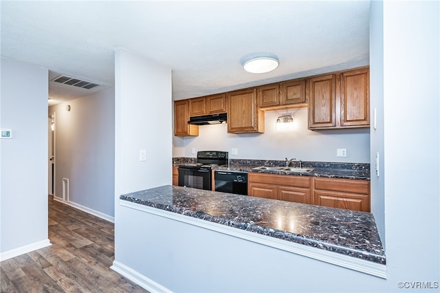 kitchen with sink, dark hardwood / wood-style floors, black appliances, and dark stone counters