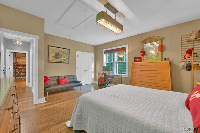 bedroom featuring light wood-style flooring, baseboards, and attic access