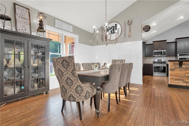 dining area featuring high vaulted ceiling, a notable chandelier, and wood finished floors