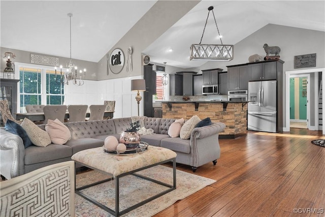 living area featuring dark wood-style floors, high vaulted ceiling, and a notable chandelier