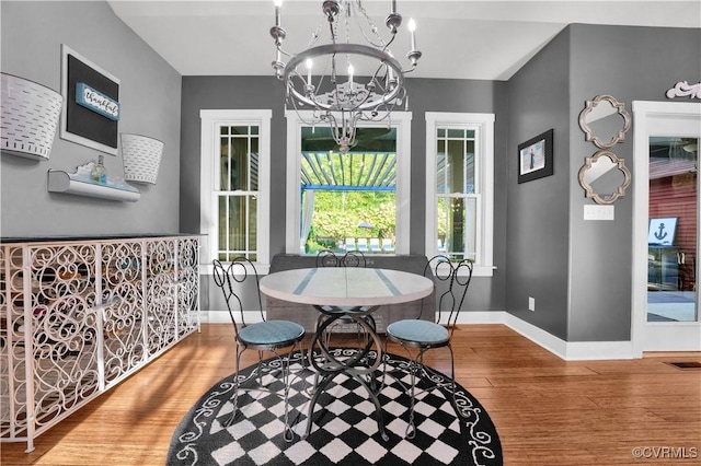 dining space featuring baseboards, wood finished floors, visible vents, and an inviting chandelier