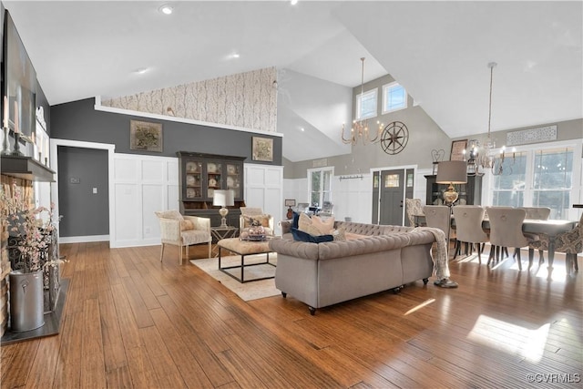 living area featuring high vaulted ceiling, wood finished floors, and an inviting chandelier