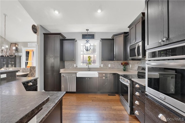 kitchen featuring appliances with stainless steel finishes, dark countertops, pendant lighting, and a sink