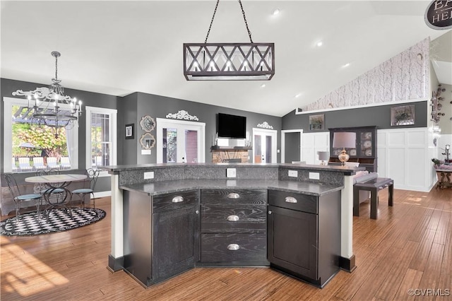 kitchen featuring a chandelier, hanging light fixtures, open floor plan, dark cabinets, and light wood-type flooring