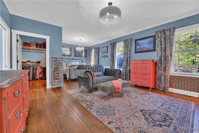 interior space featuring baseboards, wood finished floors, a spacious closet, crown molding, and a chandelier