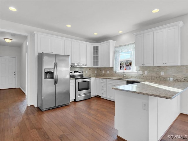 kitchen with kitchen peninsula, sink, white cabinets, hardwood / wood-style flooring, and stainless steel appliances