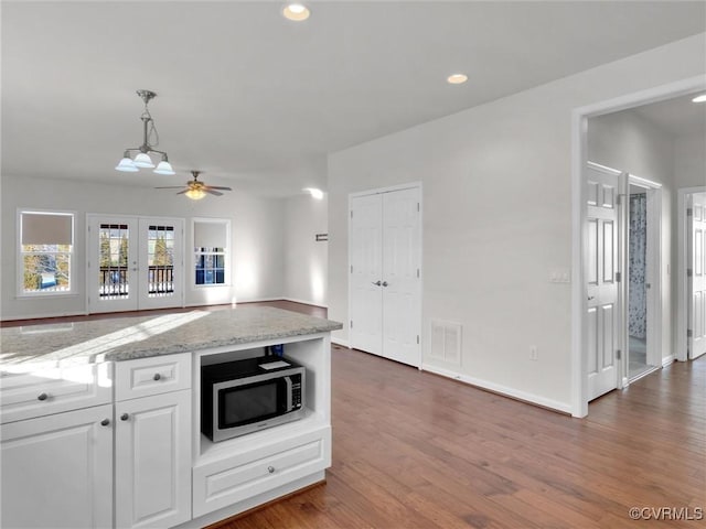 kitchen featuring pendant lighting, ceiling fan, dark hardwood / wood-style flooring, white cabinetry, and light stone countertops