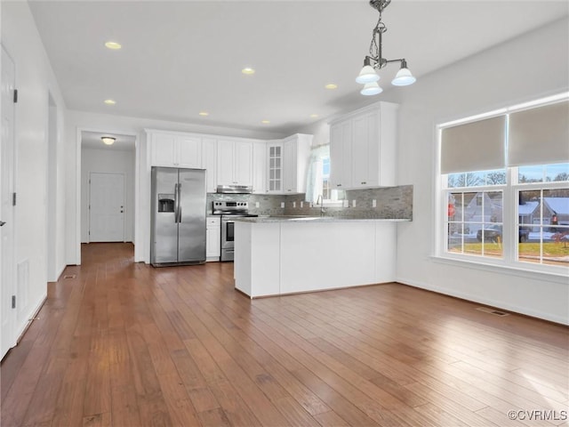 kitchen with stainless steel appliances, white cabinetry, kitchen peninsula, and decorative backsplash