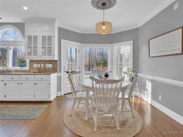 dining space featuring crown molding, light wood-type flooring, and sink