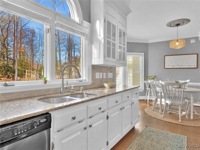 kitchen with decorative backsplash, stainless steel dishwasher, sink, white cabinets, and pendant lighting