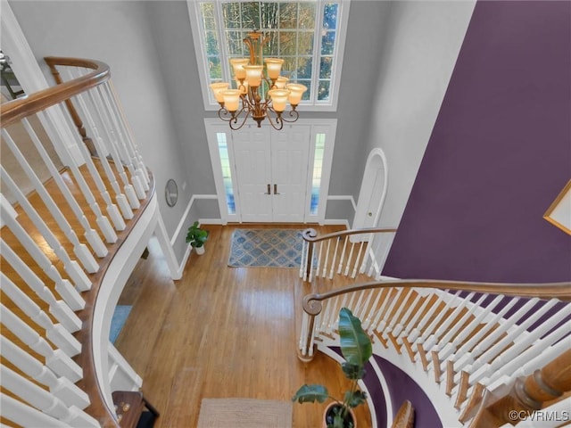 entrance foyer with a high ceiling, an inviting chandelier, and wood-type flooring