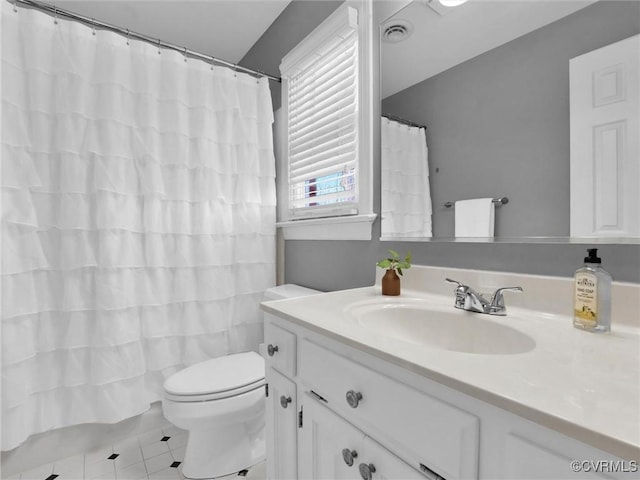 bathroom with toilet, vanity, and tile patterned flooring