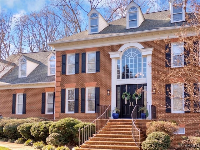 georgian-style home featuring brick siding and a shingled roof