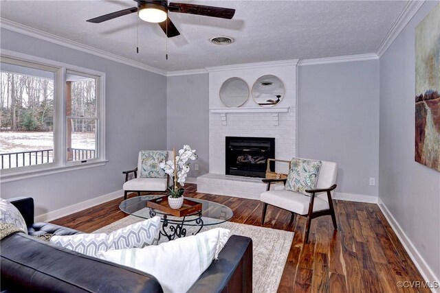 living room featuring crown molding, a fireplace, a textured ceiling, ceiling fan, and dark hardwood / wood-style floors