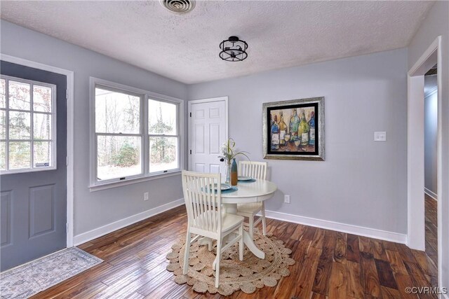 dining space with plenty of natural light, a textured ceiling, and dark wood-type flooring