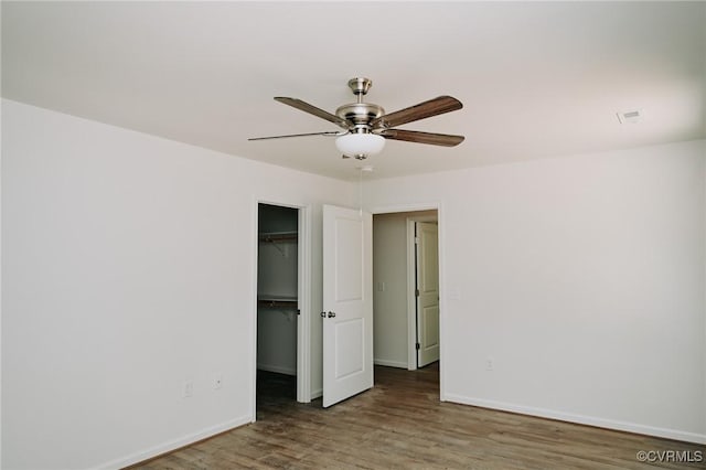 unfurnished bedroom with hardwood / wood-style flooring, a closet, a spacious closet, and ceiling fan