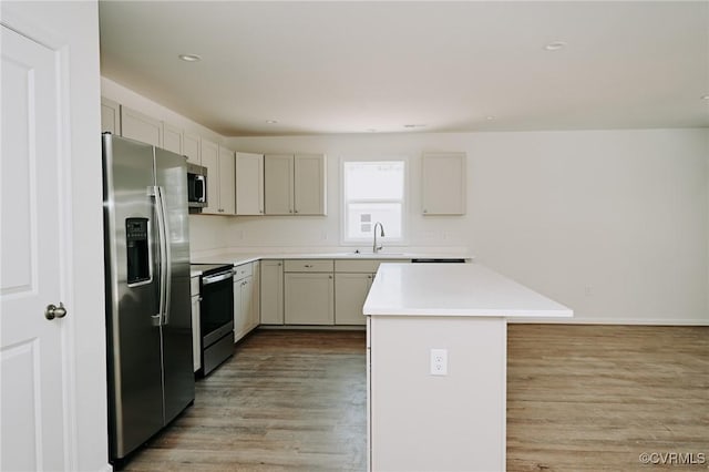 kitchen with sink, a center island, light hardwood / wood-style flooring, and appliances with stainless steel finishes