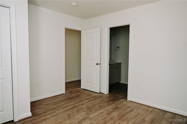 unfurnished bedroom with hardwood / wood-style flooring and ensuite bath