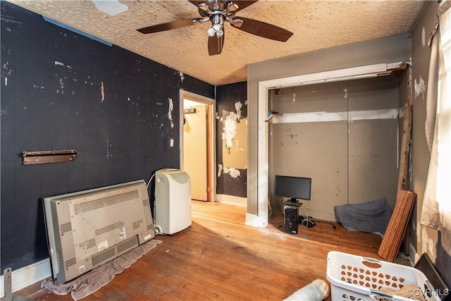 bedroom featuring hardwood / wood-style floors, a textured ceiling, a closet, ceiling fan, and heating unit