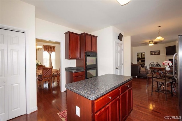 kitchen with dark wood-type flooring, ceiling fan, a center island, and double oven