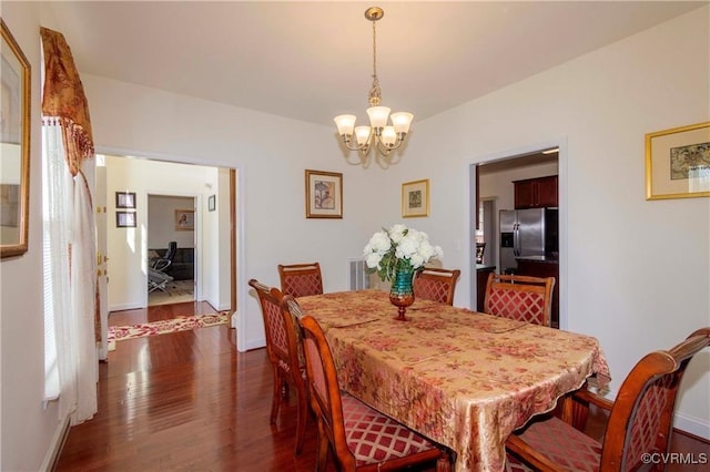 dining area featuring dark wood-type flooring and an inviting chandelier