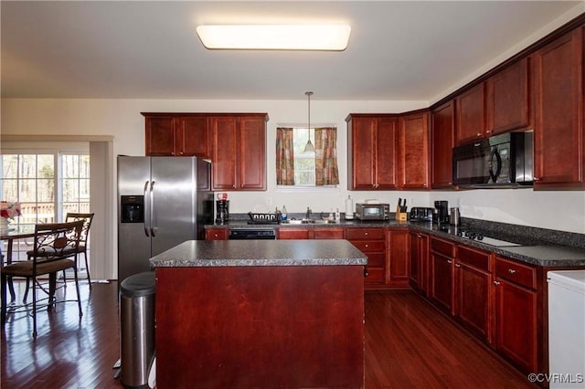 kitchen featuring sink, dark hardwood / wood-style floors, a center island, black appliances, and decorative light fixtures