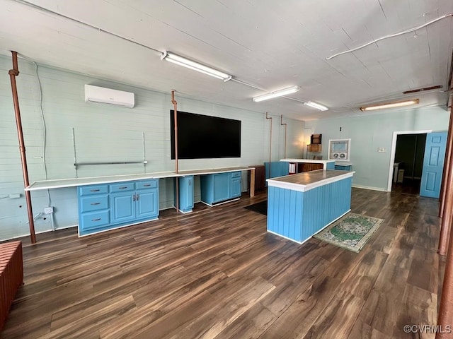 interior space featuring built in desk, a kitchen island, dark wood-type flooring, a wall mounted air conditioner, and blue cabinets