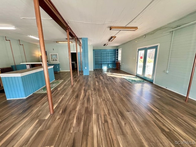 unfurnished living room with french doors, wood walls, and dark hardwood / wood-style flooring