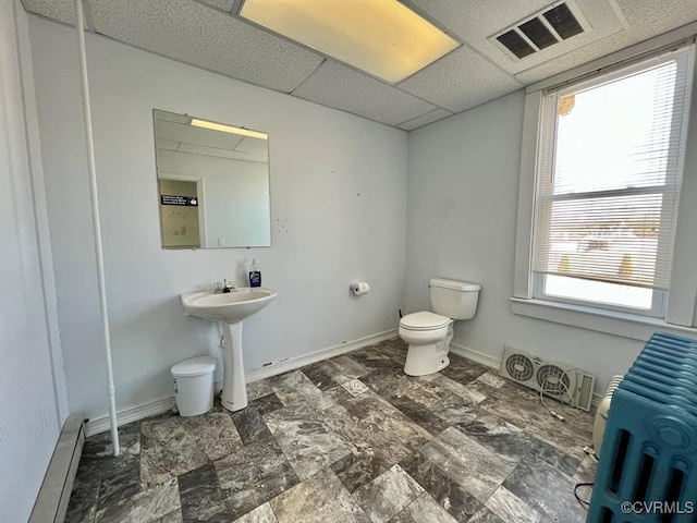 bathroom with a baseboard radiator, radiator, sink, toilet, and a drop ceiling