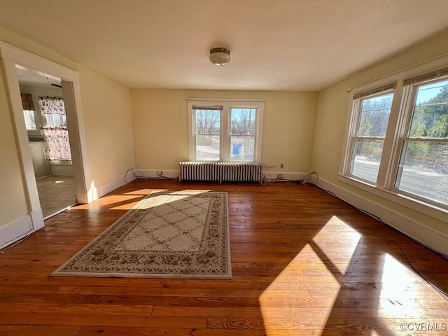 unfurnished room with hardwood / wood-style floors, a healthy amount of sunlight, and radiator