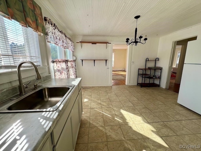 kitchen with sink, white refrigerator, pendant lighting, and an inviting chandelier