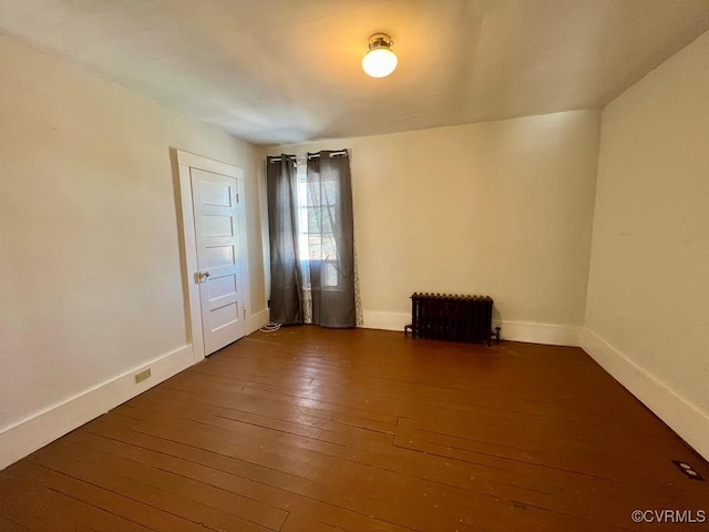 empty room featuring radiator and dark hardwood / wood-style flooring