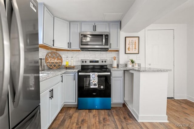 kitchen with light stone countertops, backsplash, dark hardwood / wood-style floors, and stainless steel appliances