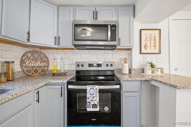 kitchen with light stone counters, appliances with stainless steel finishes, and tasteful backsplash