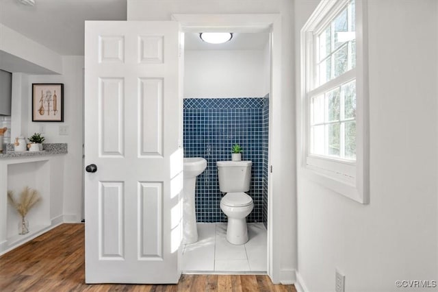 bathroom with hardwood / wood-style flooring, tile walls, and toilet