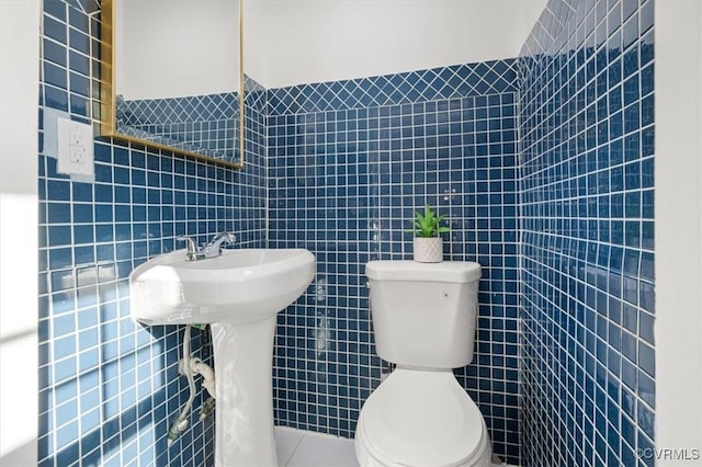 bathroom featuring toilet and tile walls