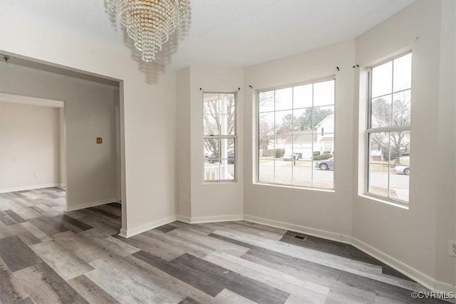 empty room featuring wood-type flooring and a chandelier