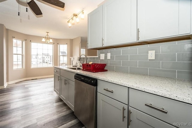 kitchen featuring light stone countertops, tasteful backsplash, hanging light fixtures, stainless steel dishwasher, and sink