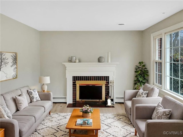 living room featuring a fireplace, light wood-type flooring, and baseboard heating