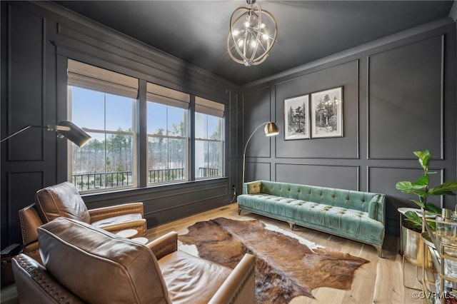 sitting room with a notable chandelier, a decorative wall, and wood finished floors