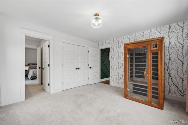 unfurnished bedroom with a closet, light colored carpet, baseboards, and wallpapered walls