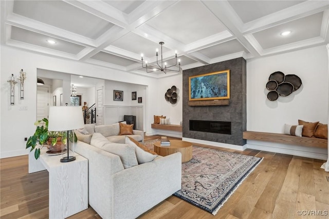 living area featuring a large fireplace, hardwood / wood-style floors, coffered ceiling, and beam ceiling