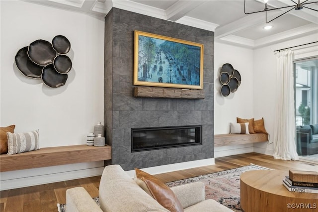 living room featuring coffered ceiling, a tiled fireplace, ornamental molding, beamed ceiling, and wood finished floors