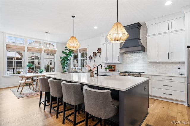 kitchen featuring light countertops, a kitchen island with sink, and white cabinetry