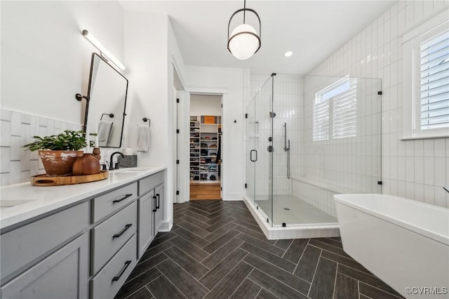 full bathroom featuring double vanity, a freestanding bath, a spacious closet, a sink, and a shower stall