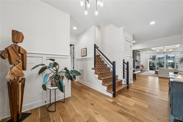 interior space with light wood-style flooring, a notable chandelier, recessed lighting, a decorative wall, and stairway