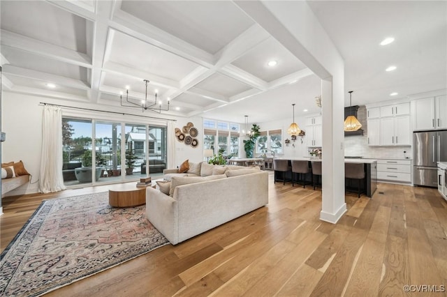 living room with a chandelier, light wood-style flooring, recessed lighting, coffered ceiling, and beam ceiling