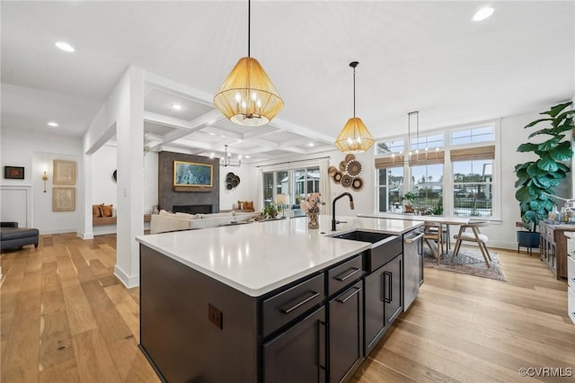 kitchen featuring open floor plan, light countertops, hanging light fixtures, and a center island with sink