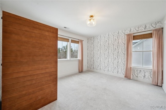 spare room with light carpet, wallpapered walls, and visible vents