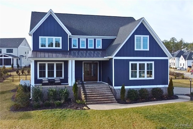 view of front facade with roof with shingles, a porch, a standing seam roof, metal roof, and a front lawn